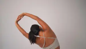 Studio portrait of mixed race female athlete stretching her body