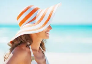 Happy young woman in swimsuit and beach hat looking on. Fun Summer Hats