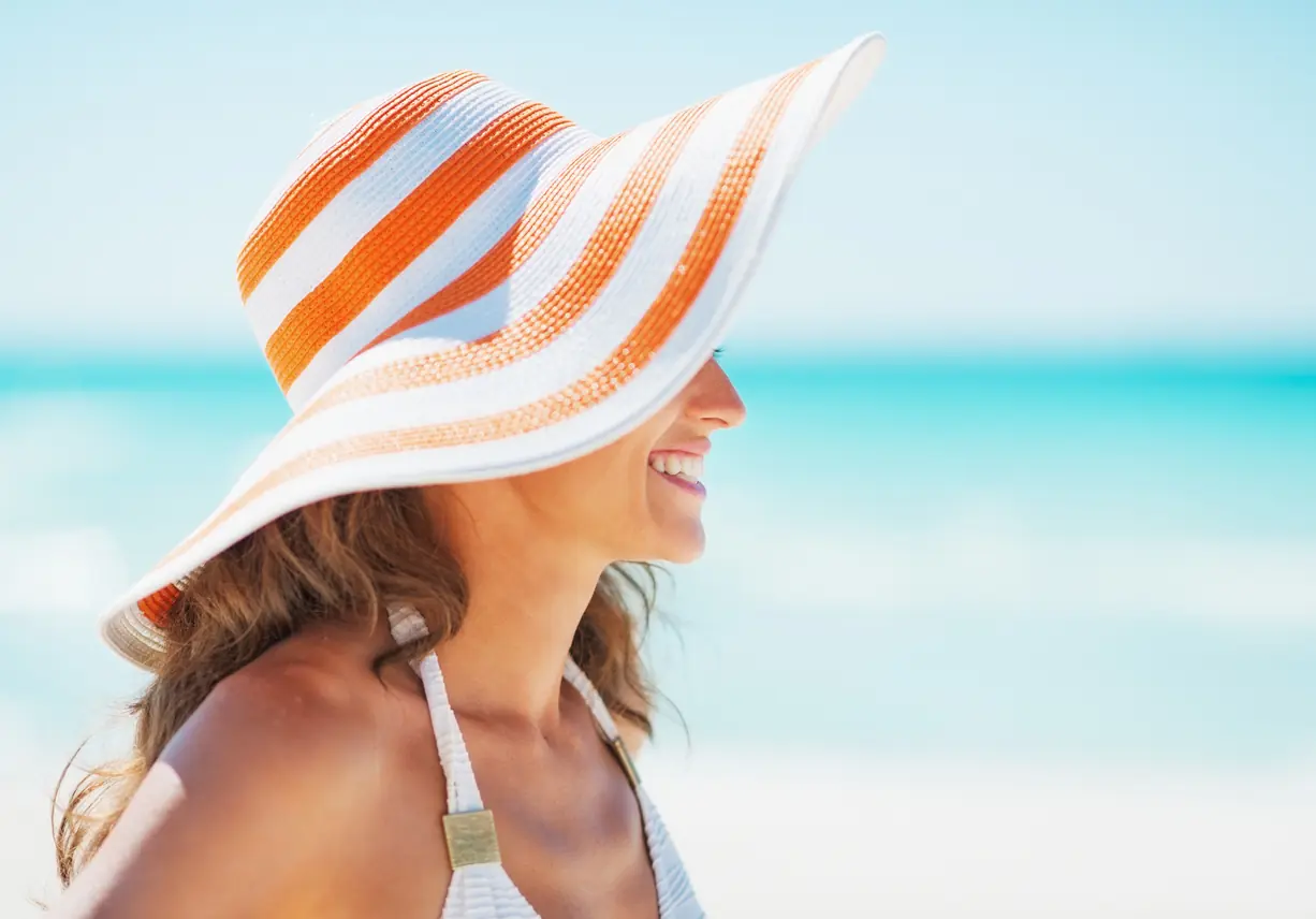 Happy young woman in swimsuit and beach hat looking on. Fun Summer Hats