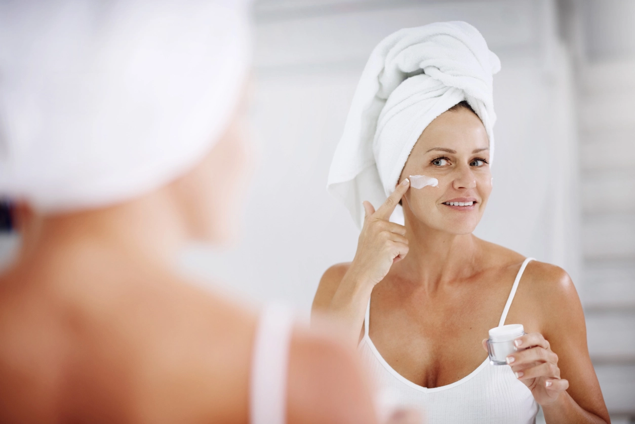 Best drugstore skincare products, woman applying face cream with towel on head