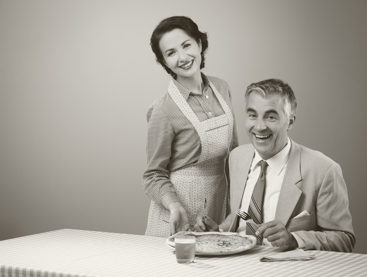 Smiling wife serving dinner; black and white image; old fashioned