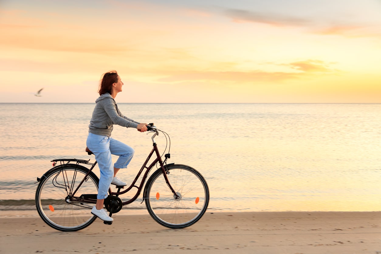Exercise is good for cognitive health, woman riding her bike on the beach
