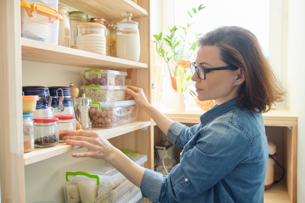 Woman looking at cupboard to check out her selection of foods.