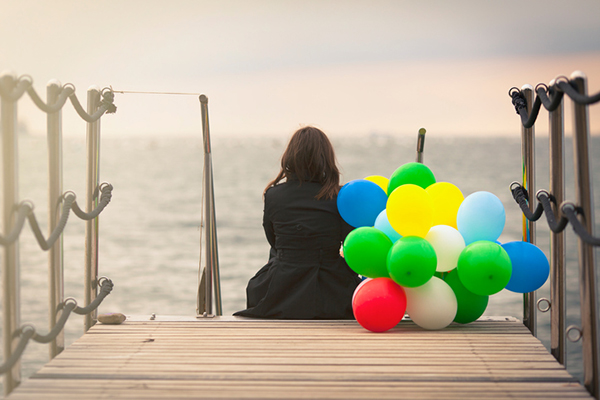 women sitting on a dock with balloons