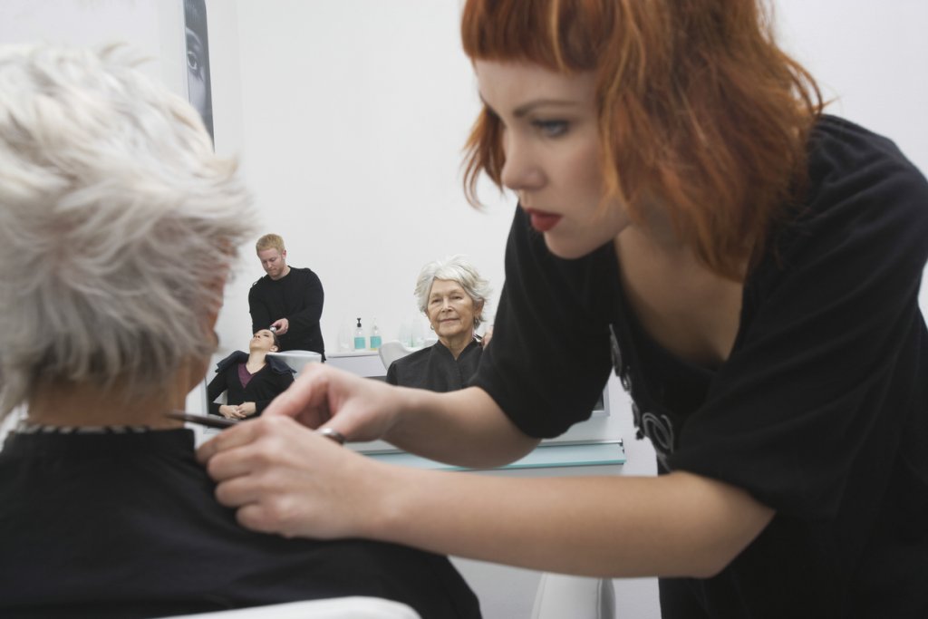 Female Stylist Giving Haircut To Senior Woman's Hair