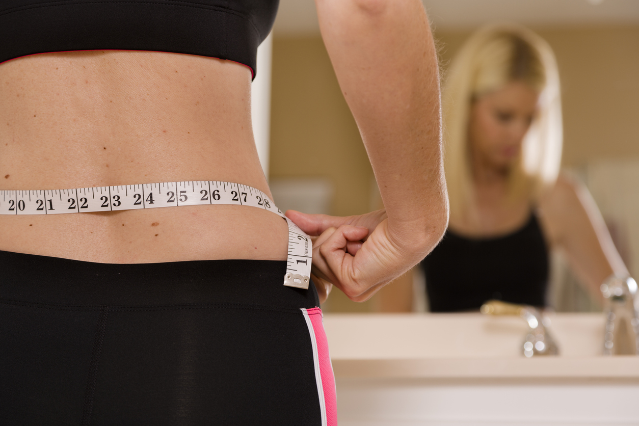 Woman measuring waist with measuring tape,Excess belly fat and