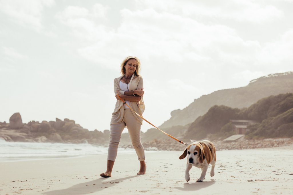 Woman Walking Dog on Beach
