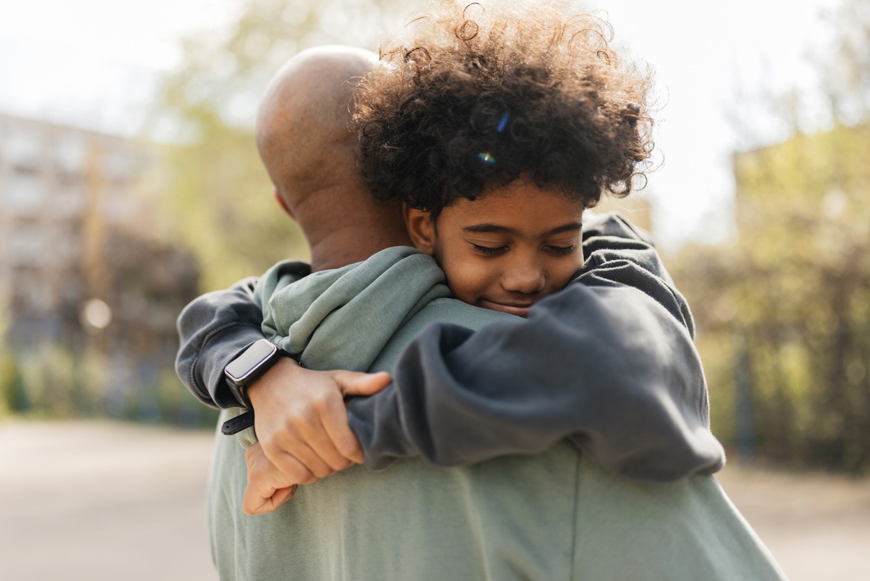 Tender hug shared between a child and adult. Remembering Dad on Father's Day