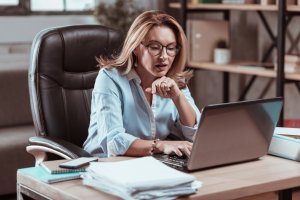 Hard-working businesswoman wearing glasses reading important e-mail