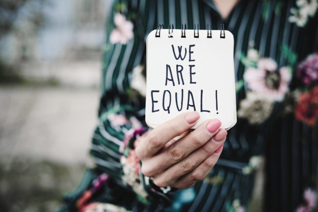 woman shows notepad with the text we are equal