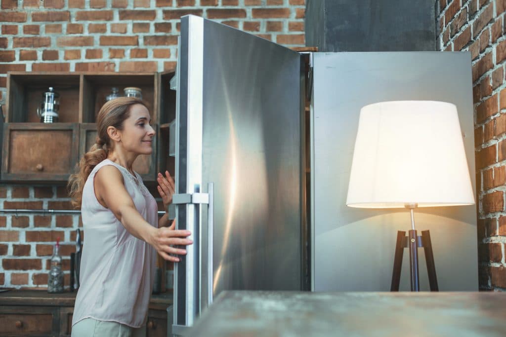 Menopause relief - Mature woman cools off in front of fridge menopause hot flashes