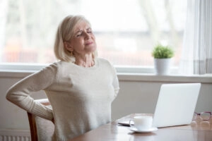 woman holding her back because her posture might be causing it to hurt.