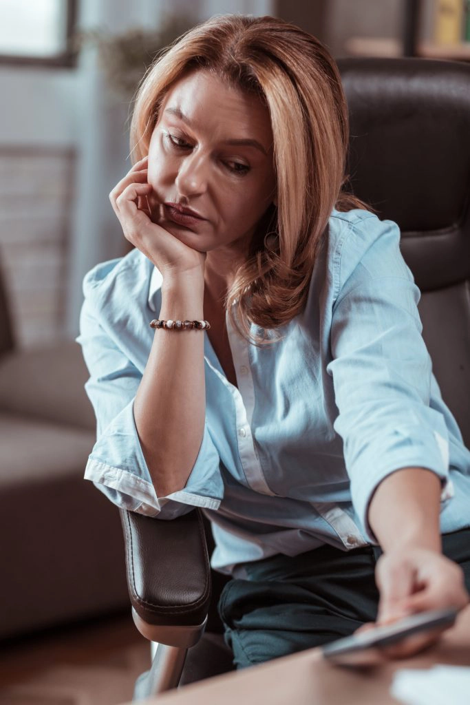 Blonde-haired mature woman feeling sad not getting call from her husband