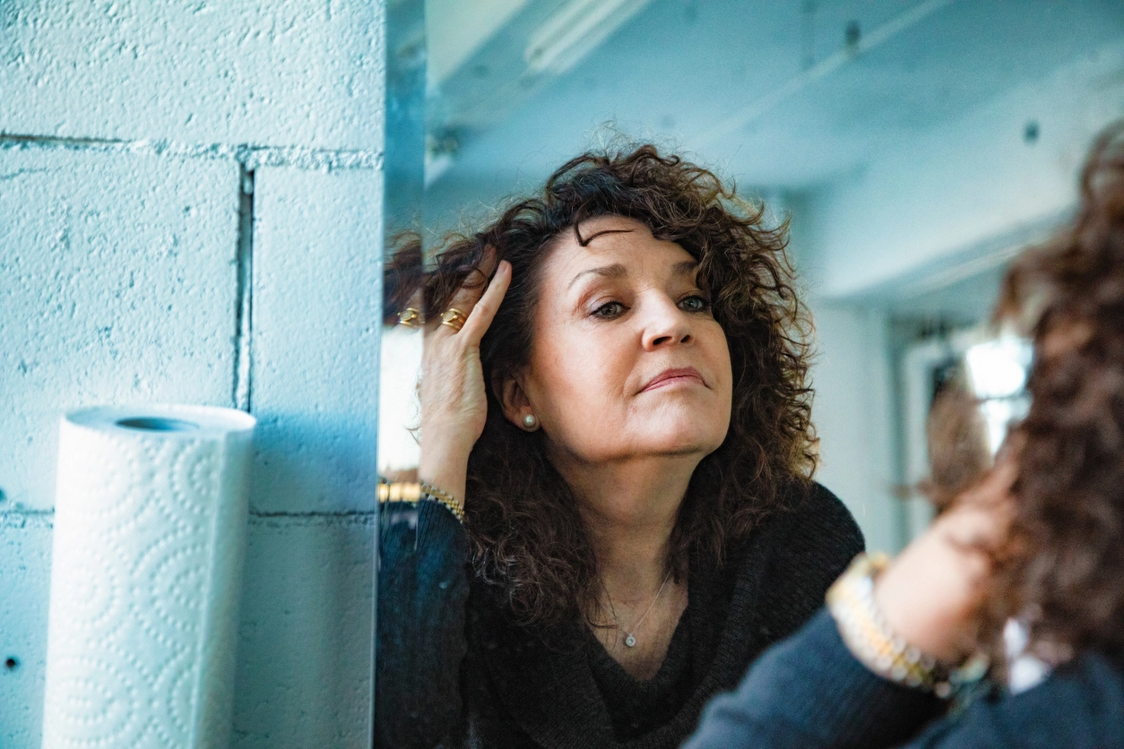 Woman with curly hair looking at herself in the mirror