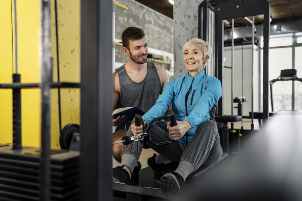 Beginners guide to gym equipment, woman on row machine with personal trainer