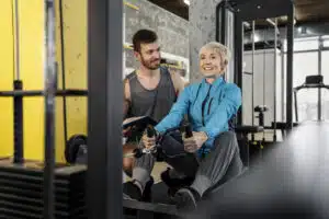 Beginners guide to gym equipment, woman on row machine with personal trainer
