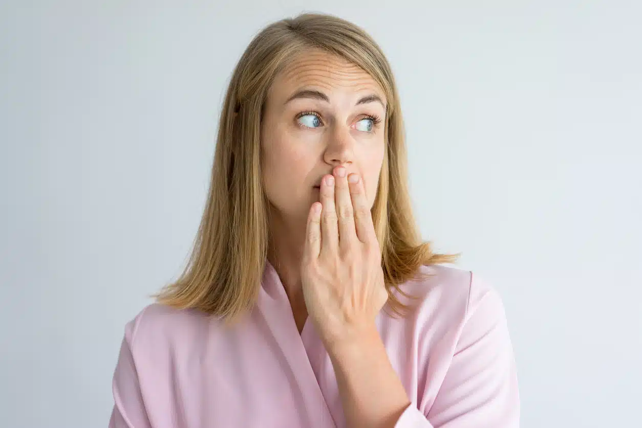 Portrait of shocked young woman covering mouth