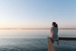 Tips for a long and healthy life - woman sitting on a dock looking a the ocean