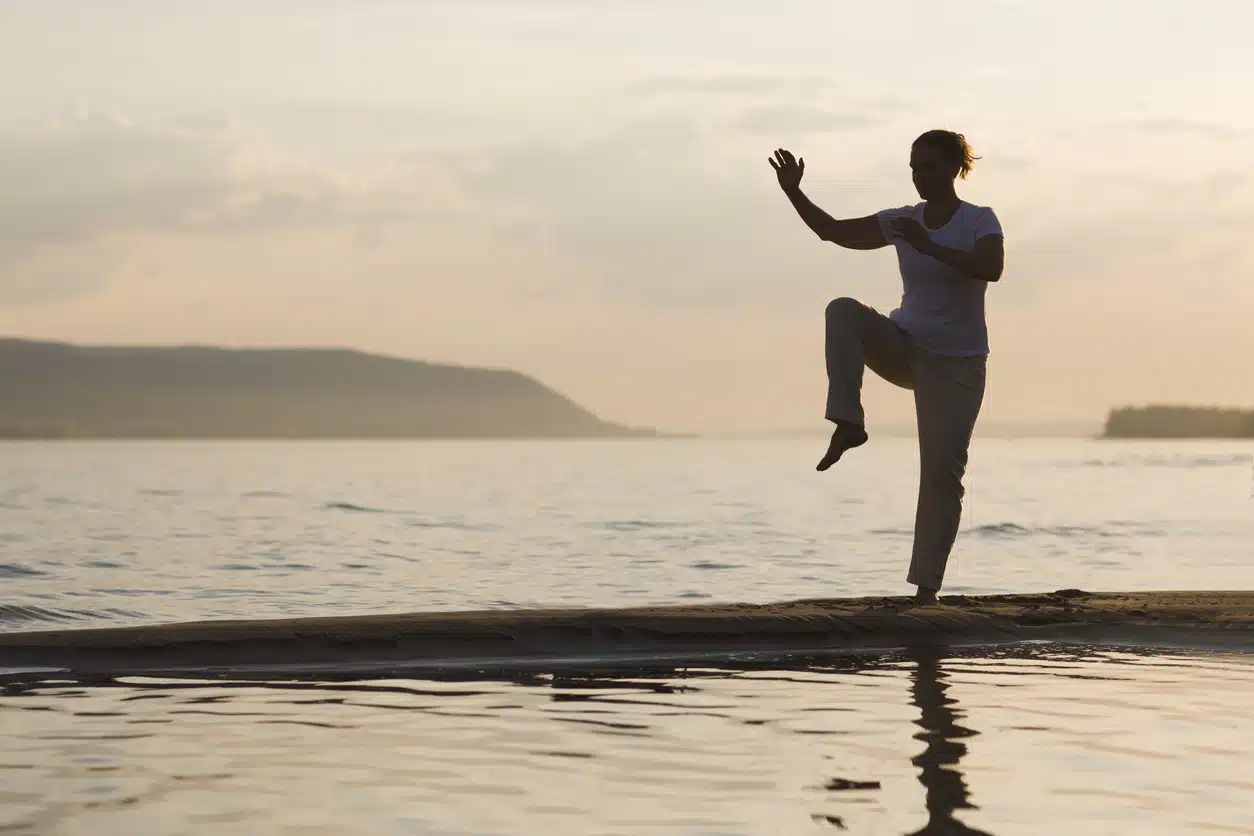 Woman practicing tai chi on a beach building balance