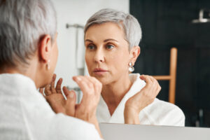 woman looking in mirror; Hyaluronic Acid