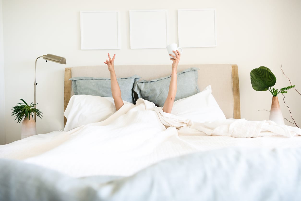 woman laying in bed with coffee waking up