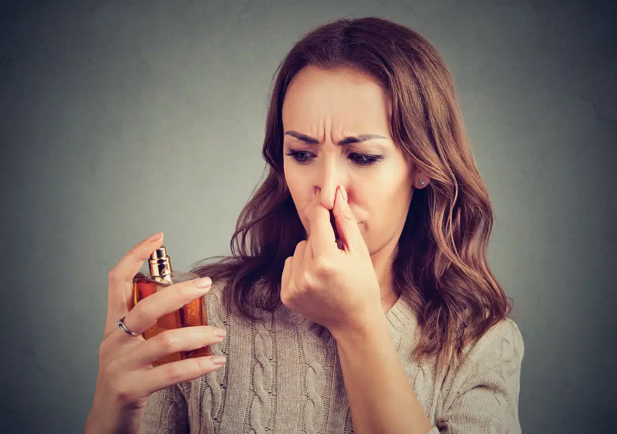 Woman smelling a perfume that's stinky