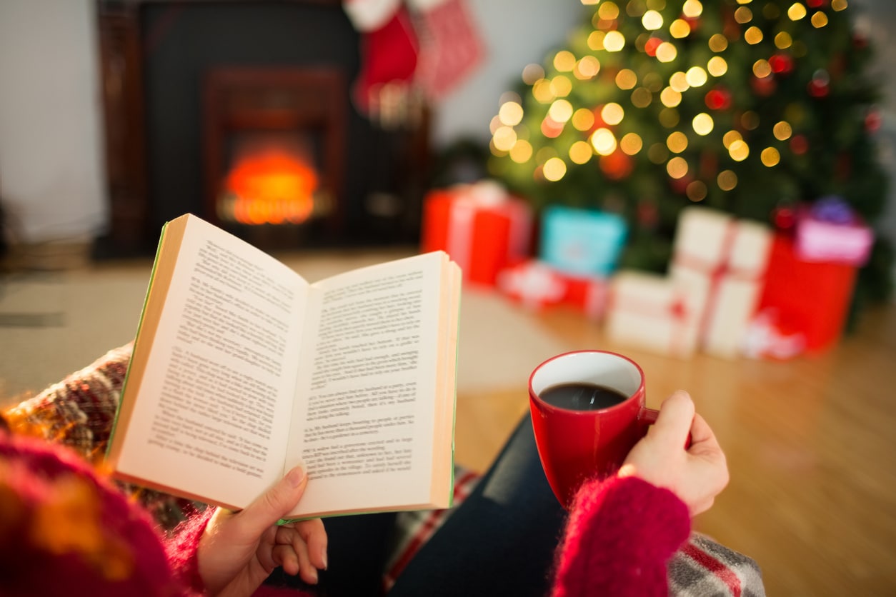 December reading list - reading a book by the Christmas Tree with a cup of coffee