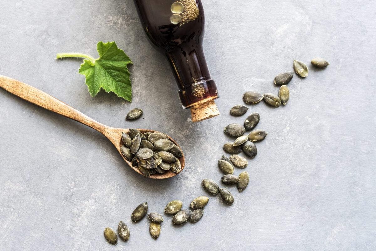 Pumpkin seeds on a wooden spoon and pumpkin seed oil