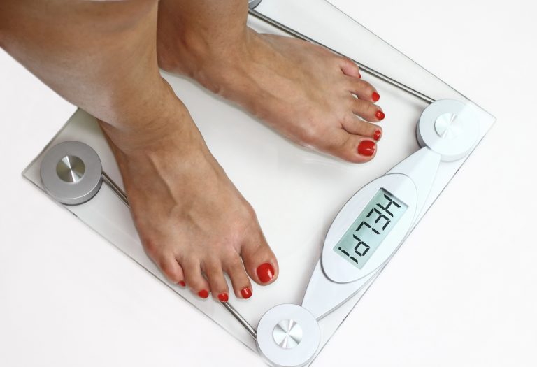 How to Break A Weight Loss Plateau woman standing on scale