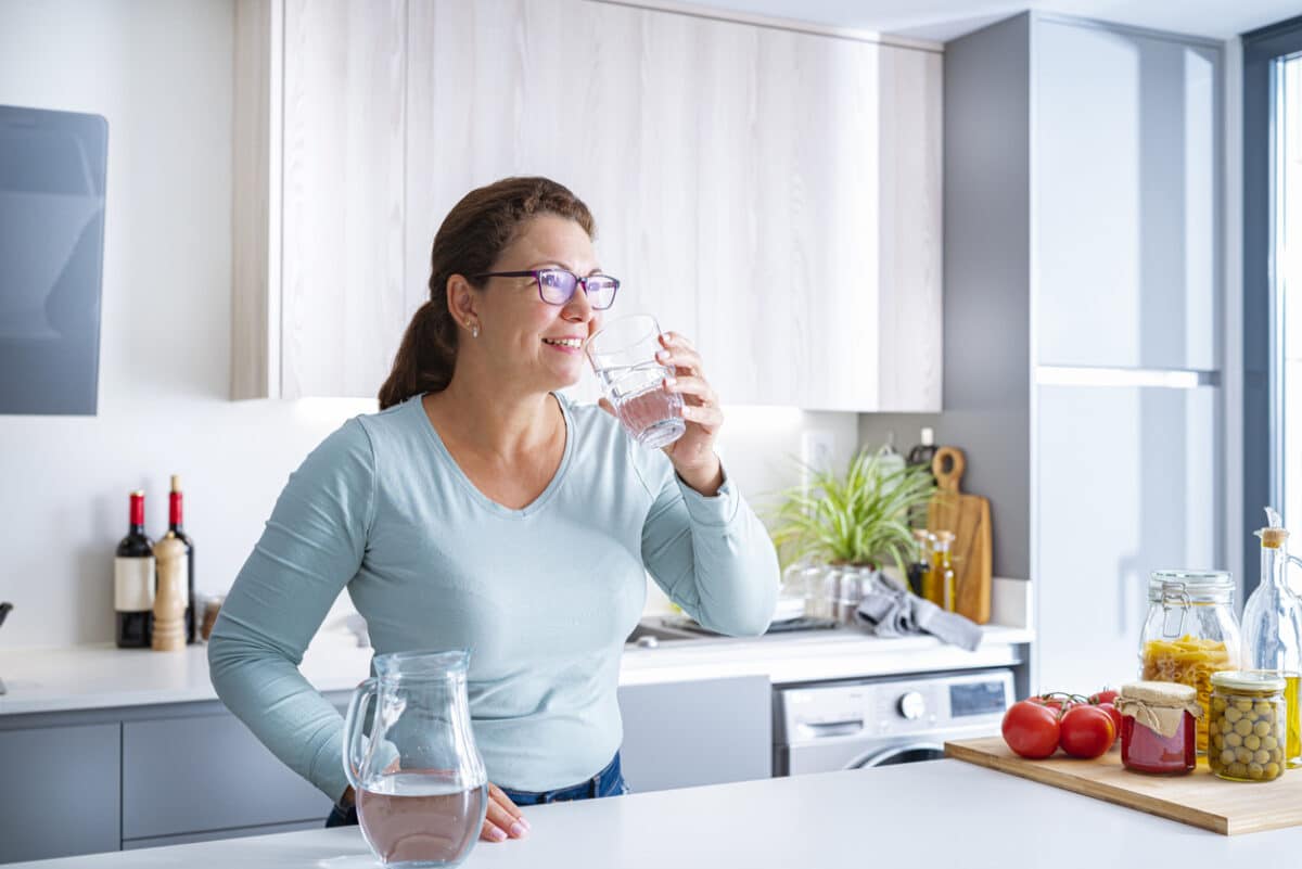 woman drinking water in her kitchen
