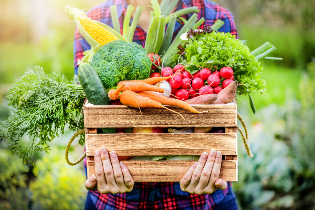 Woman holding a box of vegetables to help lower your cholesterol