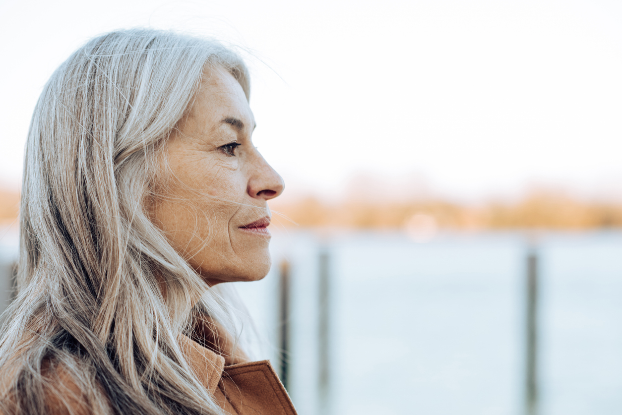Is hearing loss leaving you lonely and isolated? -- Headshot of a thoughtful mature woman looking at the distance