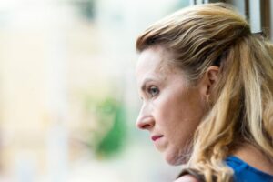 Depressed woman looking out window to show Keratin can be used as a treatment for depression