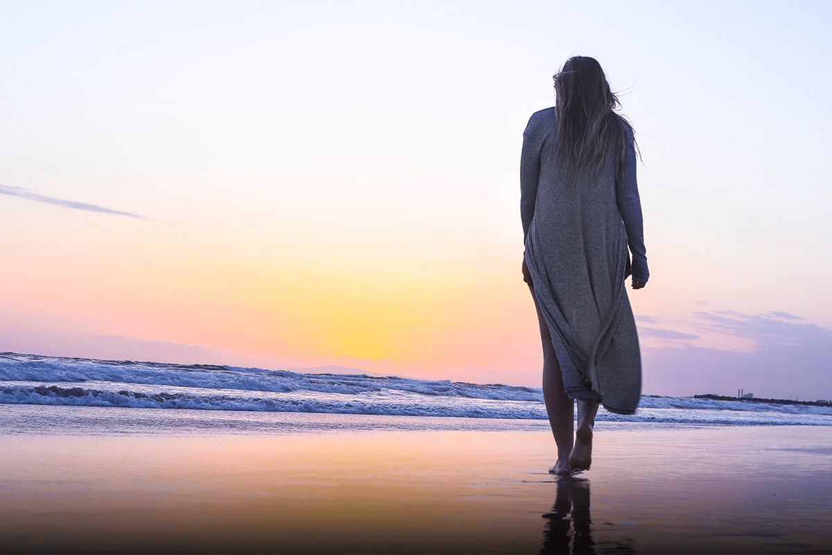 Morning routine for aging well; woman walking on the beach at sunrise