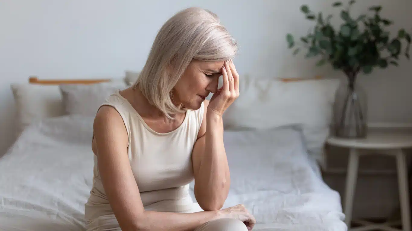 Woman on bed with a headache, bad night sleep