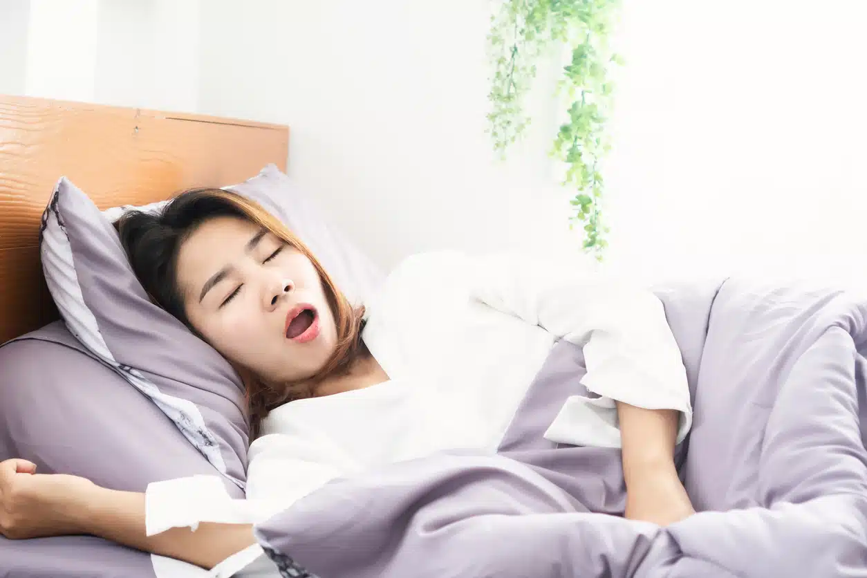 Asian woman snoring in bed with mouth open