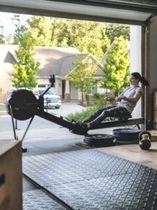 Best exercise equipment - woman in garage home gym working out on rowing machine