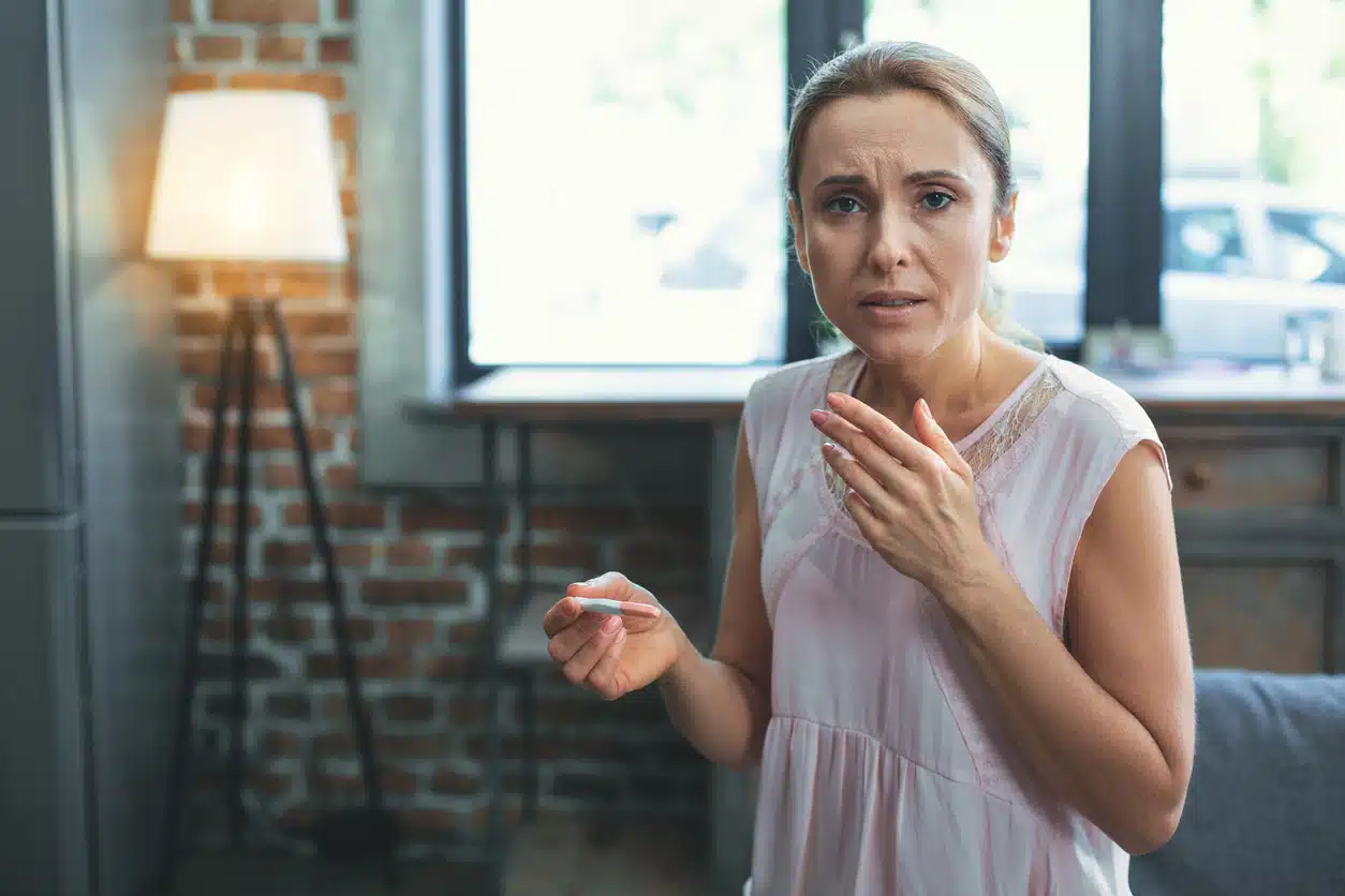 Mature woman looking at pregnancy test looking unhappy