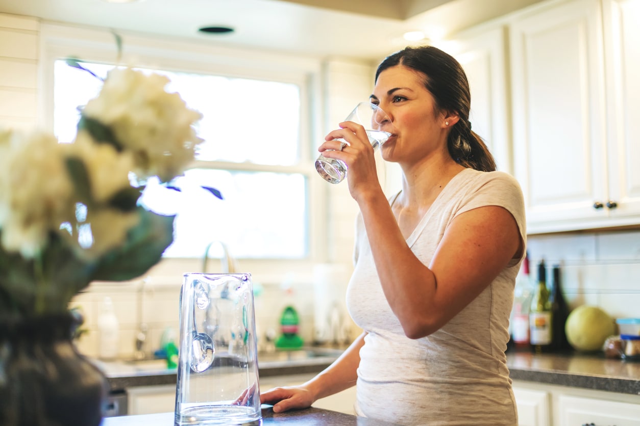 Woman in kitchen drinking water