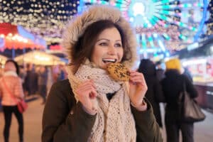 Top guilty pleasures for women over 50; Woman eating a chocolate chip cookie; Winter carnival