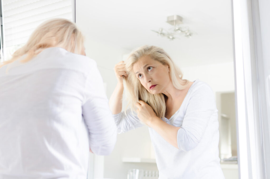 Natural hair loss remedies - woman looking at her hair in the mirror
