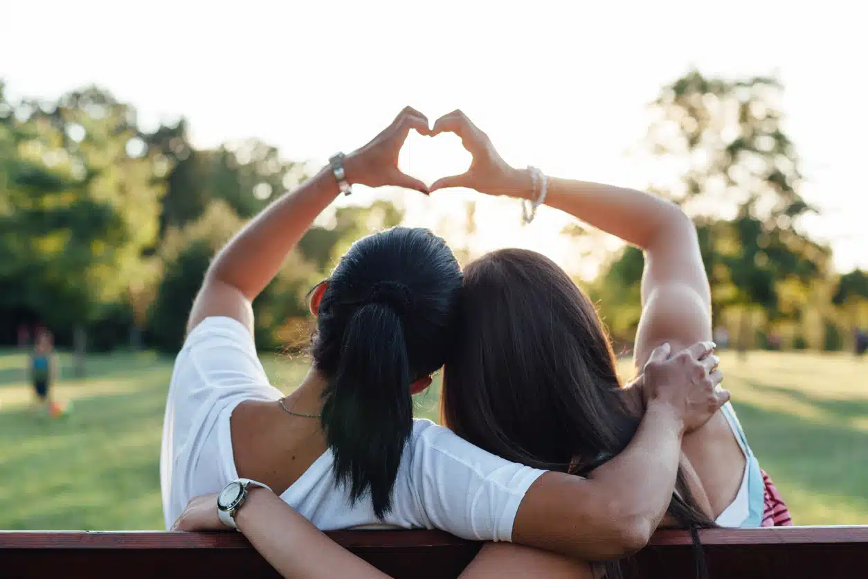 Two women on a bench - mother and daughter - holding up hands in the shape of a heart