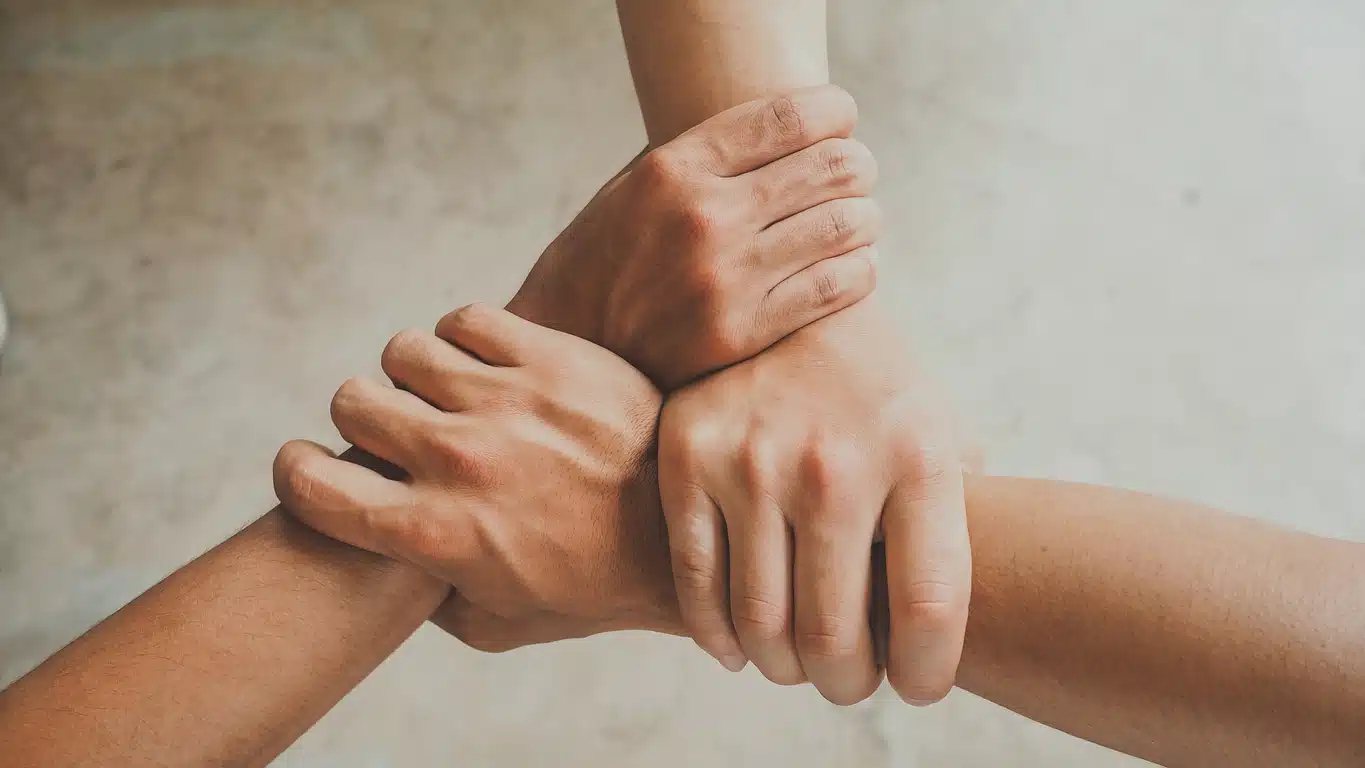Three hands intertwined to show strength together