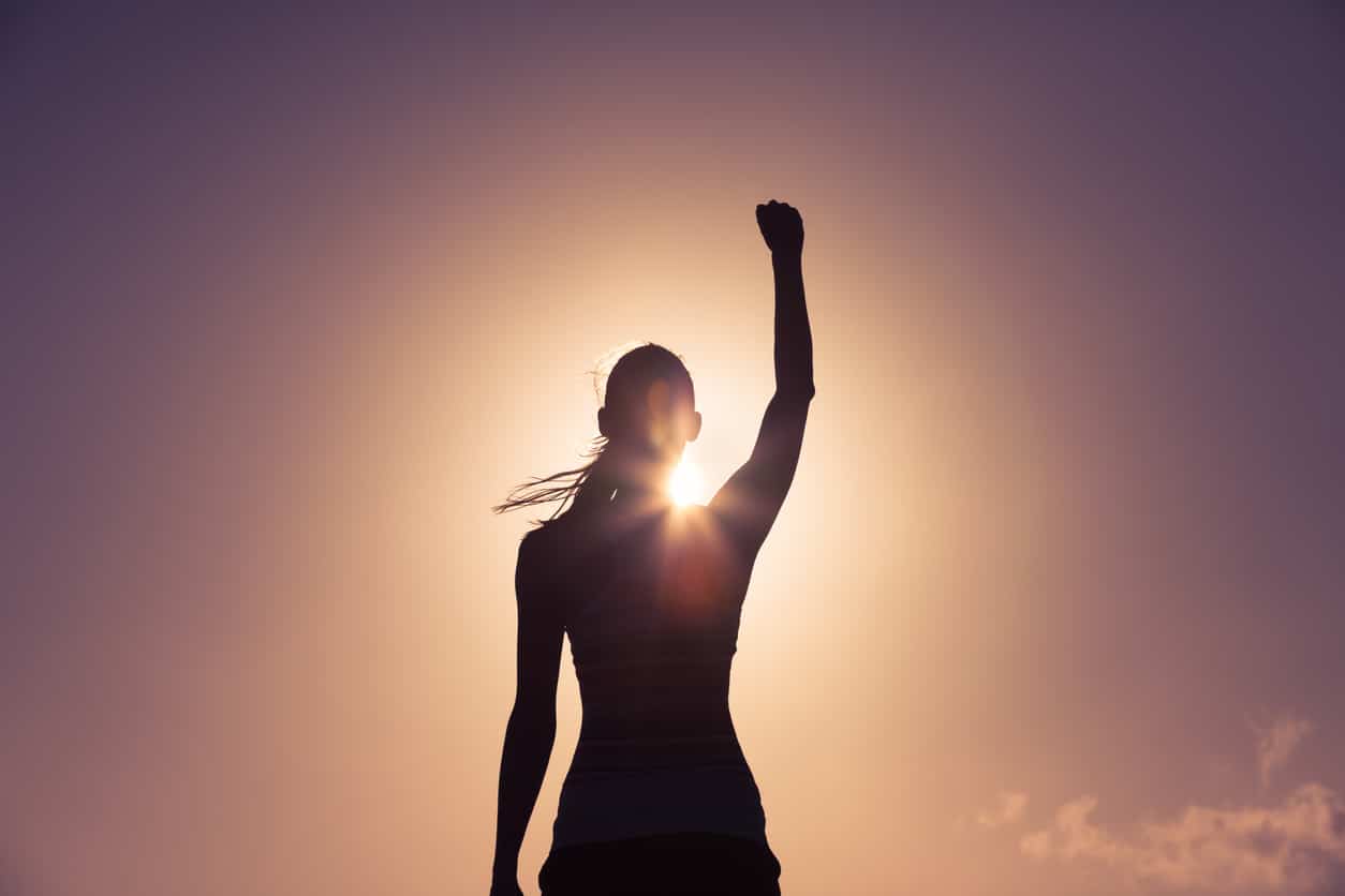 Woman raising her arm in the air celebrating; empowered woman; success