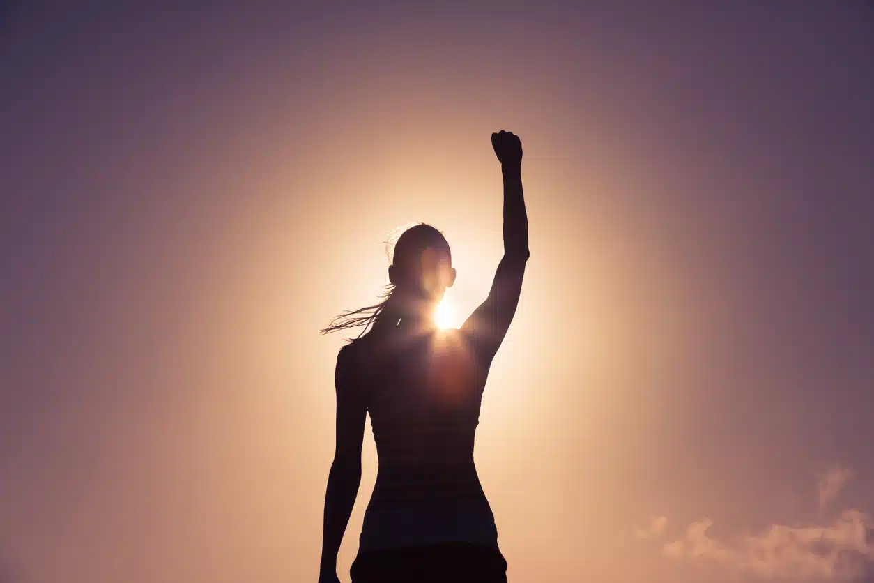 Woman raising her arm in the air celebrating; empowered woman; success