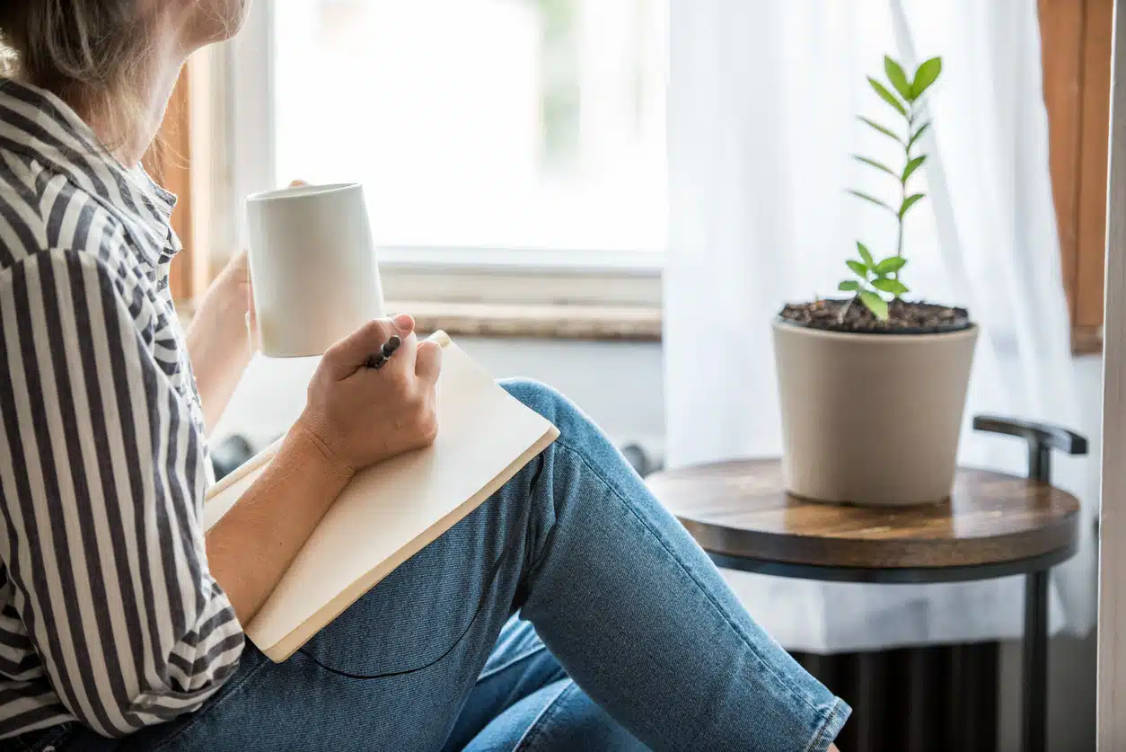 Woman writing in journal while drinking coffee