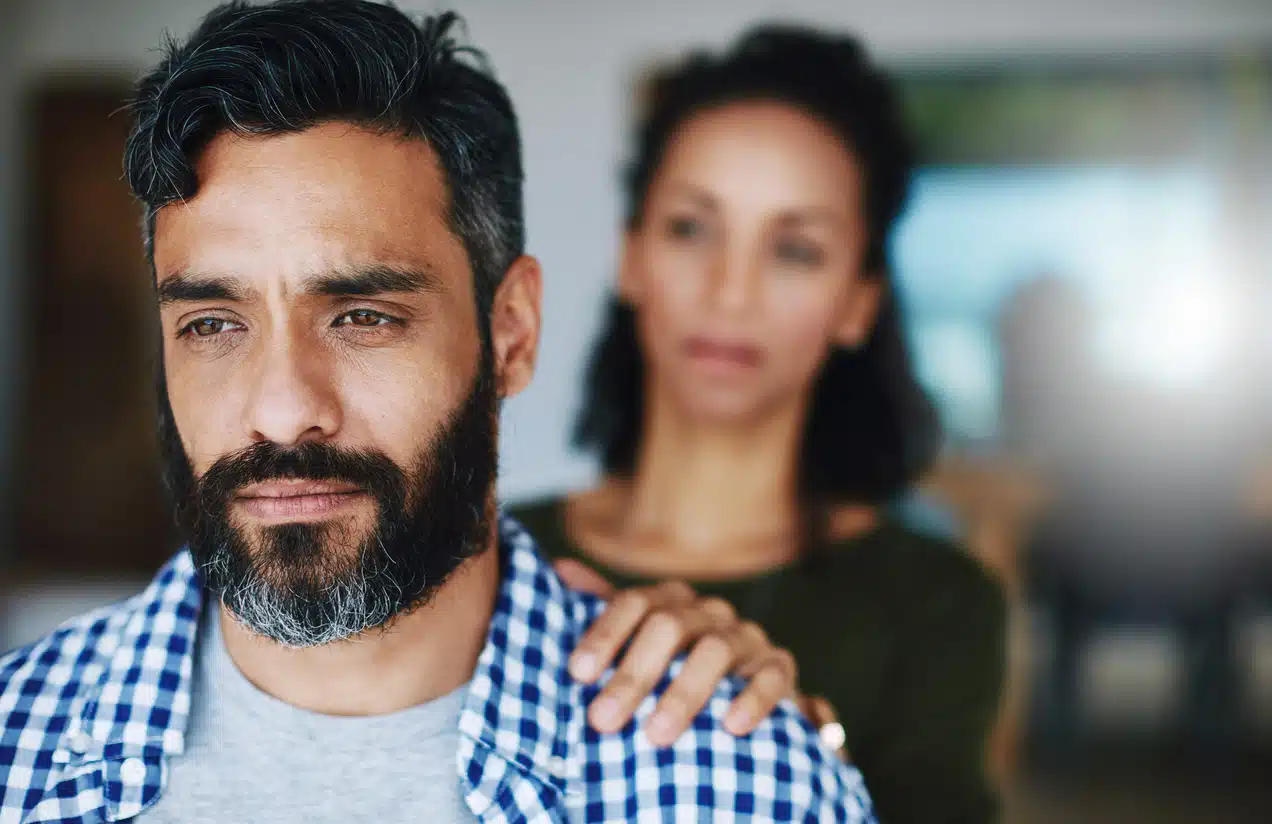 Man grieving while woman comforts him