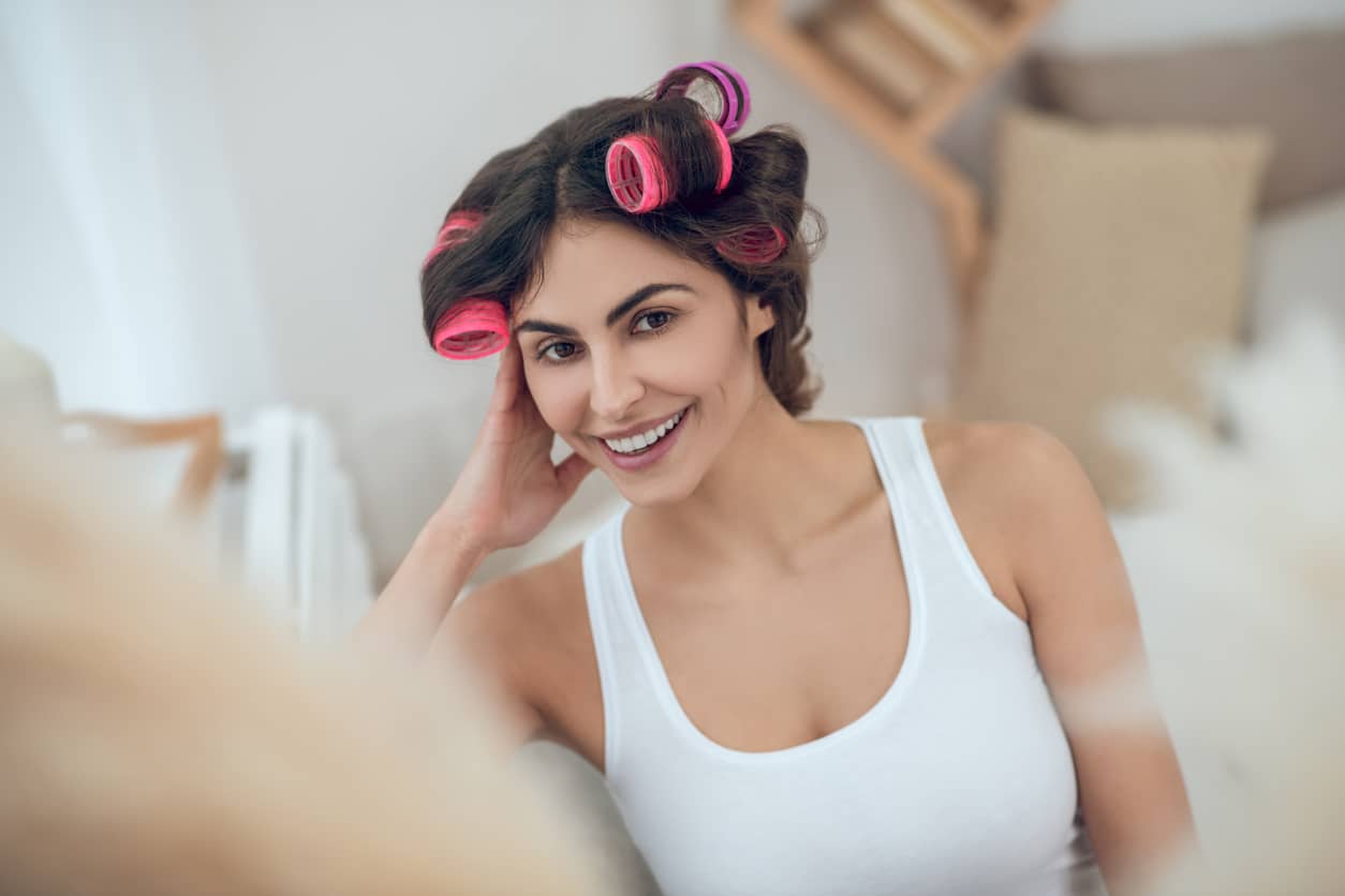 Woman with no-heat curlers in medium-length brown hair