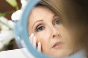 Woman looking in mirror for dermal repair formula