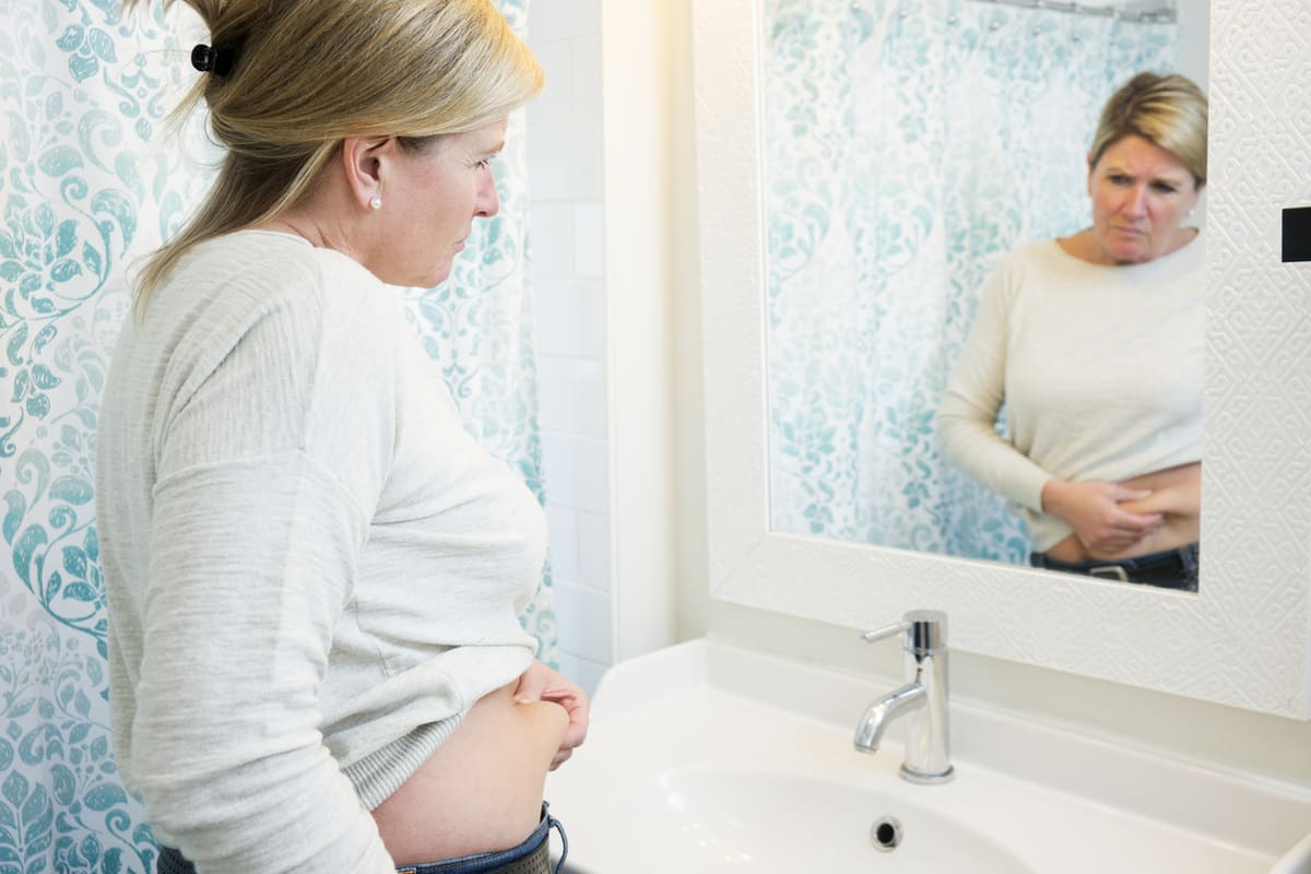 woman pinching fat looking in mirror